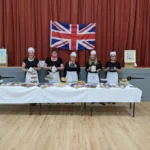 Ladies dressed up as traditional Victorian maids with British goods in hand.